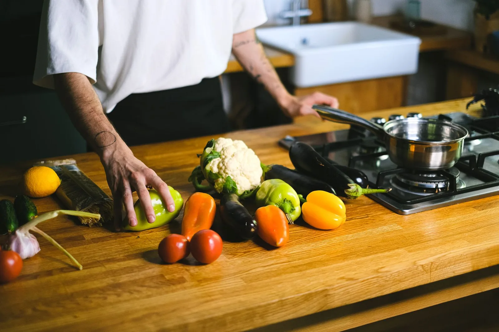 Des mains disposent des légumes sur un plan de travail.